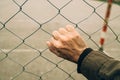 Male hand on chainlink fence