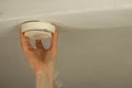 Male hand changing the battery and fixing the smoke alarm on ceiling of a home. Home or office safety concept. Royalty Free Stock Photo