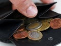 Male hand checking black leather wallet with euro coins, close-up of a open purse with loose change Royalty Free Stock Photo