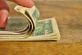 Male hand checking and counting a heap of American money US currency, USD on the wooden background as a symbol of wealth Royalty Free Stock Photo