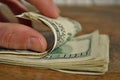 Male hand checking and counting a heap of American money US currency, USD on the wooden background as a symbol of wealth Royalty Free Stock Photo