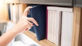 Male hand picking blue book on bookshelf