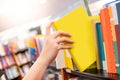 Male hand choosing yellow book from bookshelf