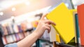 Male hand choosing yellow book from bookshelf