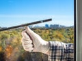 male hand cleans a home window glass by squeegee