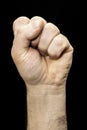 Male hand clenched into a fist on the black background