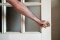 Male hand closes a white painted wooden door with frosted glass in a country house.