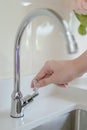 Male hand closing water tap in kitchen