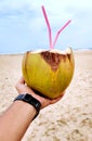 Male hand with a coconut on the beach