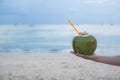 Male hand with a coconut on the beach