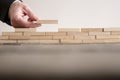 Male hand completing building wall of wooden bricks