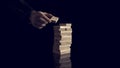 Male hand creating or building a tower of many wooden blocks over black background Royalty Free Stock Photo