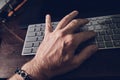 Male hand on desk with finger on computer keyboard