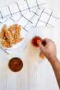 Male hand dipping chicken fingers into sauce, overhead view. Top view