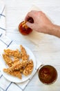 Male hand dipping chicken strips into sauce, top view. Overhead