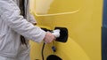 Male hand disconnects power connector into EV car