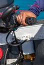 Male hand driving a inflatable boat holding the tiller of an outboard motorboat.