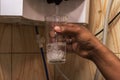 A male hand filling drinking water from a water purifier into a glass