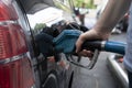 Male hand fills car with gasoline at the gas station holding a gaspump nozzle