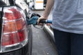 Male hand fills car with gasoline at the gas station holding a gaspump nozzle