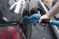 Male hand fills car with gasoline at the gas station holding a gaspump nozzle