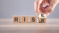 Male hand flipping wooden cube with Risk to Rise