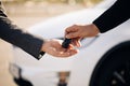 Male hand gives a car keys to male hand in the car dealership close up. Unrecognized auto seller and a man who bought a Royalty Free Stock Photo