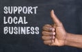 Male hand giving the thumbs up gesture to the phrase Support Local Business