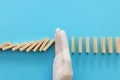 A male hand in glove stopping the domino effect. covid 19 or coronavirus blocking concept Royalty Free Stock Photo