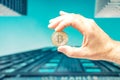 Male hand hold a bitcoin, modern office buildings in the background, bitcoin concept, business background