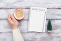Male hand hold cup of coffee and notebook with goals for 2018. Planning and motivation for the new year concept. Top view. Royalty Free Stock Photo
