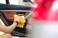 Male hand hold yellow microfiber towel and wipes the door with leather panel closeup Royalty Free Stock Photo