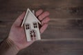 Male hand holdin a wooden house on a wooden background. Buying a house with a young family. Affordable housing. banner Royalty Free Stock Photo