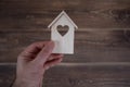 Male hand holdin a wooden house on a wooden background. Buying a house with a young family. Affordable housing. banner Royalty Free Stock Photo