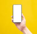 Male hand holding the black smartphone with blank screen isolated on yellow background with clipping path. Royalty Free Stock Photo