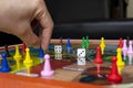 Male hand holding a blue pawn with old dices and color pawns over Colombian native board game Royalty Free Stock Photo