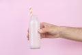 Male hand holding a bottle of milkshake  on pink background Royalty Free Stock Photo