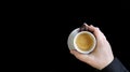 Male hand holding a coffee cup. Close up of a hand of man holding a warm mug with fresh coffee isolated on black background.