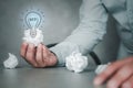 Male hand holding crumpled white paper and illuminated light bulb icons for finding great inspiration Royalty Free Stock Photo