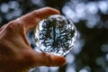 male hand holding crystal glass ball against nature background with reflections Royalty Free Stock Photo