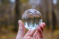 male hand holding crystal glass ball against nature background with reflections Royalty Free Stock Photo