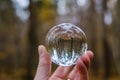 male hand holding crystal glass ball against nature background with reflections Royalty Free Stock Photo