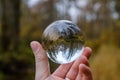 male hand holding crystal glass ball against nature background with reflections Royalty Free Stock Photo