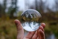 male hand holding crystal glass ball against nature background with reflections Royalty Free Stock Photo