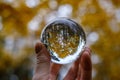 male hand holding crystal glass ball against nature background with reflections Royalty Free Stock Photo