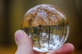 male hand holding crystal glass ball against nature background with reflections Royalty Free Stock Photo