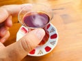 Male hand holding glass of hot Turkish tea on wooden table