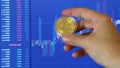 Male hand holding gold bitcoin coin and moves on BTC/USD chart background