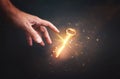 Male hand holding golden key with glowing light. Concept of success and wealth Royalty Free Stock Photo