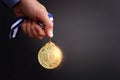 Male hand holding golden medal over dark background and light burst Royalty Free Stock Photo